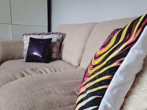 um sofá com uma almofada roxa sobre ele com um arremesso em Cosy home entire house, sleeps 7 em Wyken