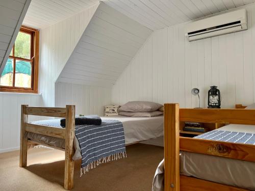 ein Schlafzimmer im Dachgeschoss mit zwei Betten und einem Fenster in der Unterkunft Cornellskop Country Stay in Botrivier