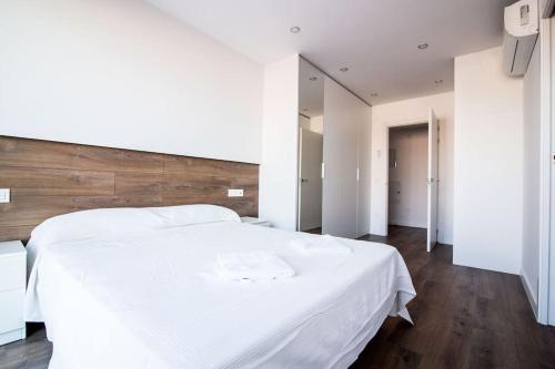 1 dormitorio con cama blanca y cabecero de madera en 3-2 Apartamento de diseño en el centro de Reus, en Reus