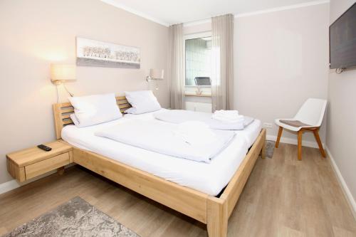 威克奧夫弗爾的住宿－Königstraße 1, Whg 43 im Strandhotel，一间卧室配有一张带白色床单和椅子的床