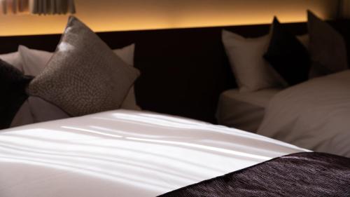 - un lit avec des draps et des oreillers blancs dans l'établissement HOTORI no HOTEL BAN, à Fujikawaguchiko