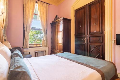 a bedroom with a bed and a cabinet and a window at Büyükada Anastasia Meziki History Mansion in Buyukada