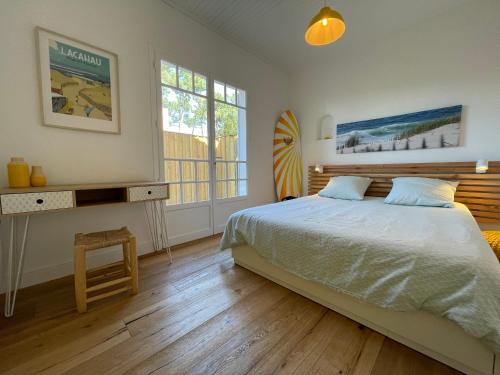 a bedroom with a bed and a desk and windows at Villa Oraihola lacanau océan plage sud in Lacanau