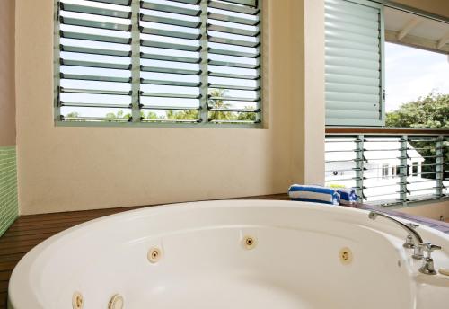 a white bath tub in a bathroom with a window at Mantra in the Village in Port Douglas