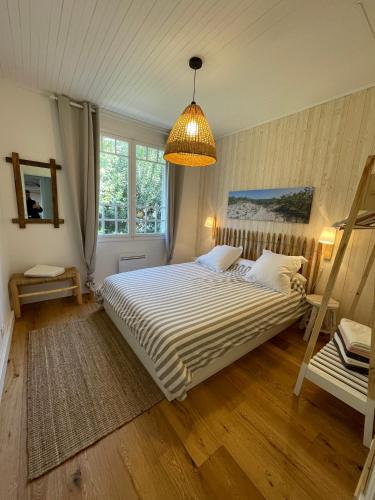 une chambre avec un grand lit et un lustre dans l'établissement Villa Oraihola lacanau océan plage sud, à Lacanau