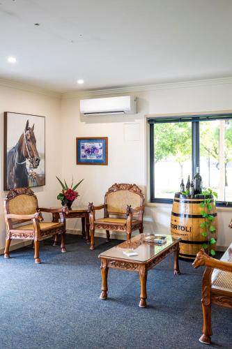 a room with chairs and a table and a barrel at Hawkesbury Race Club Motel in Windsor