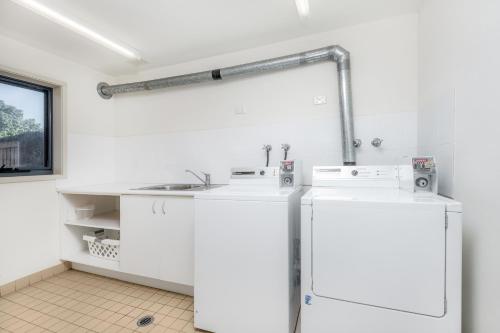 a white kitchen with two refrigerators and a sink at Hawkesbury Race Club Motel in Windsor