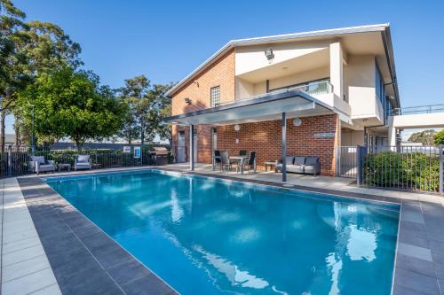 a swimming pool in front of a house at Hawkesbury Race Club Motel in Windsor