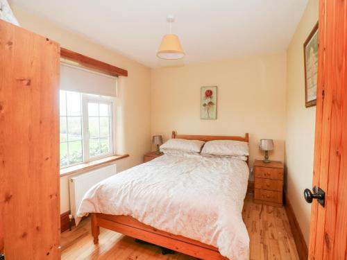 a bedroom with a bed and a window at The Granary in Castlerichard