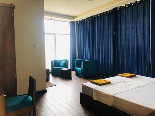 a bedroom with a bed and two blue chairs at GRAND BOLGODA RESORT in Moratuwa