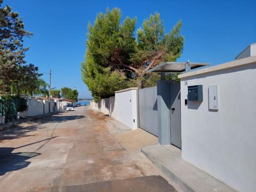 een lege straat met een wit hek en bomen bij B&B La Porta sul Mare a Porto Cesareo in Torre Squillace