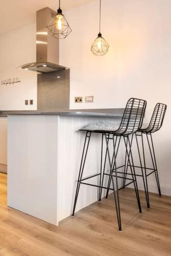 a kitchen with two bar stools and a counter at The Olive Tree with balcony and parking in Leicester