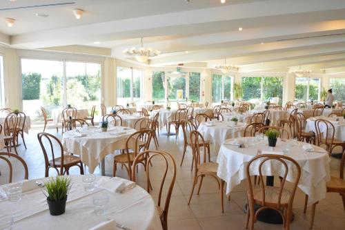 un salón de banquetes con mesas y sillas blancas en Hotel Bellevue Beach - sul mare, en Milano Marittima