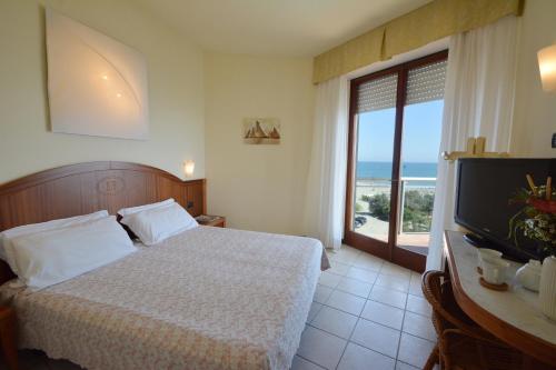 a bedroom with a bed and a television with a view of the ocean at Hotel Bellevue Beach - sul mare in Milano Marittima