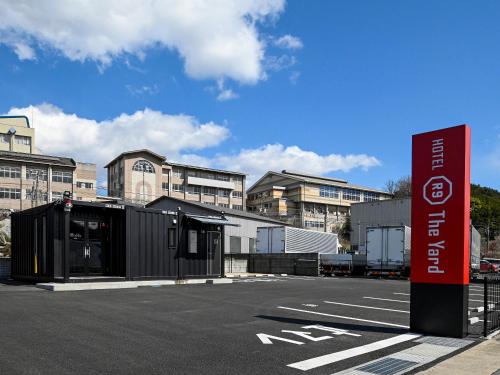 福山市にあるHOTEL R9 The Yard Fukuyamaの駐車場中の看板のある建物