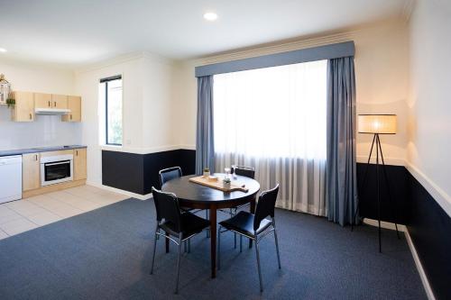 a kitchen and dining room with a table and chairs at Hawkesbury Race Club Motel in Windsor