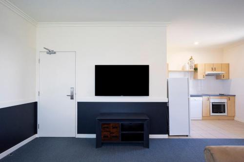a living room with a flat screen tv on a wall at Hawkesbury Race Club Motel in Windsor