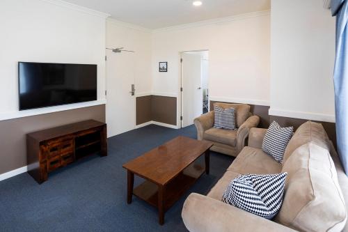 a living room with a couch and a tv at Hawkesbury Race Club Motel in Windsor