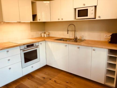 a kitchen with white cabinets and a sink and a microwave at Villa Oraihola lacanau océan plage sud in Lacanau