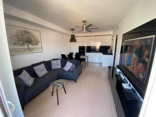a living room with a blue couch and a tv at Apartament Claudia I in Puerto de Mazarrón
