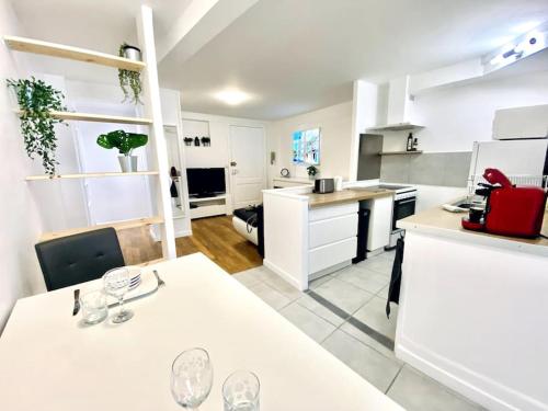 - une cuisine avec des placards blancs et une table avec des verres dans l'établissement *L’appart d’Éden* au coeur de vichy, à Vichy