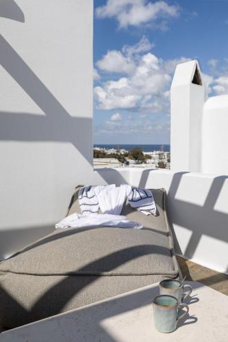 a bed on a balcony with a view of the ocean at Elena Hotel Mykonos in Mýkonos City