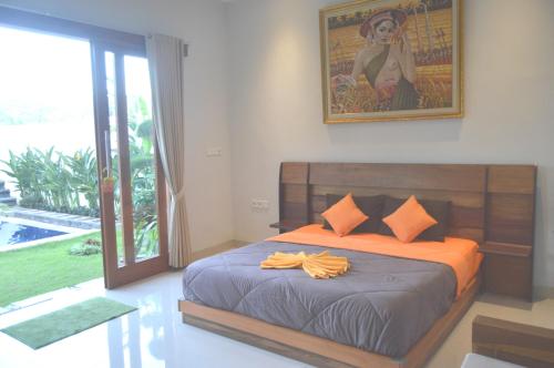 1 dormitorio con 1 cama con sábanas de color naranja y una pintura en Banyu Riris Villa Lovina Private Villa, en Banjar