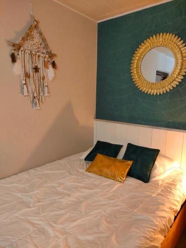 uma cama com duas almofadas e um espelho na parede em La Cabane de Thau Location Cure ou Vacances à Balaruc les Bains em Balaruc-les-Bains