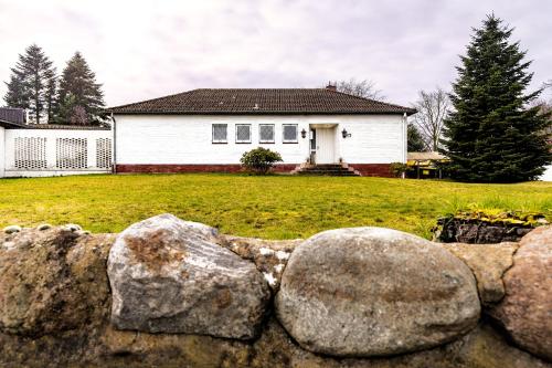 a white house with a rock fence in front of it at Haus KÖ 17 in Norderstedt