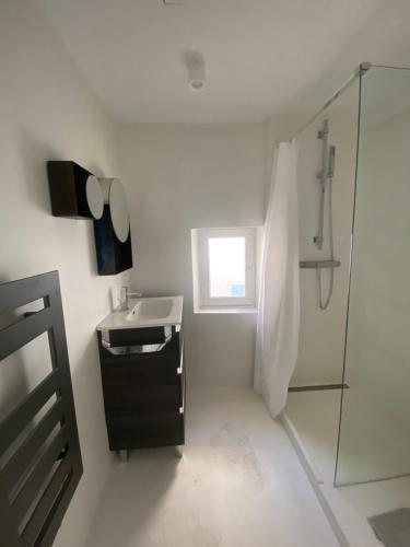 een witte badkamer met een wastafel en een douche bij L'Appartement 31 Ramatuelle Vieux Village in Ramatuelle