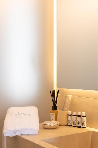 a shelf with a towel and five bottles on it at Elena Hotel Mykonos in Mýkonos City