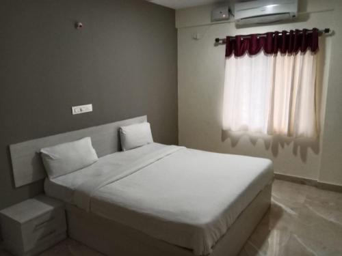 班加羅爾的住宿－PRIDE MANYATA，卧室配有白色的床和窗户。