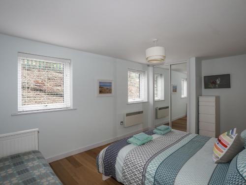 a white bedroom with a bed and a mirror at Ty Glyn in Criccieth