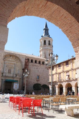 un grupo de mesas y sillas en un edificio con una torre en Apartamentos La Luna, en La Solana