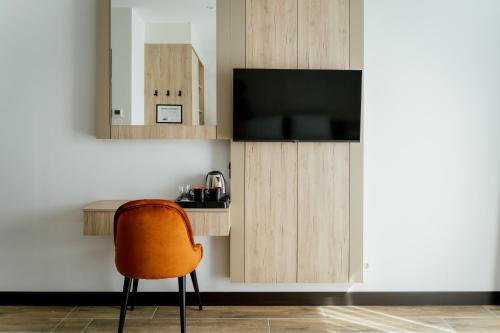 Habitación con silla y TV. en Lamede en Wiener Neustadt