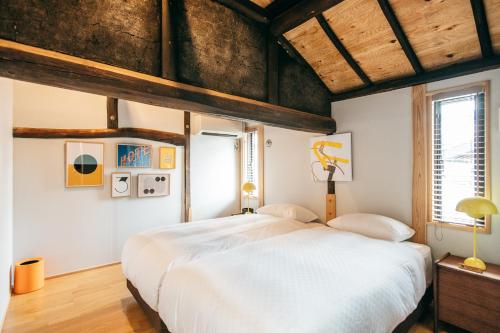 - une chambre avec un grand lit blanc et des plafonds en bois dans l'établissement Yado Charinko, à Gose
