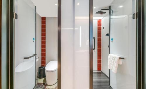 a bathroom with a toilet and a glass shower door at Houhai Hotel in Beijing
