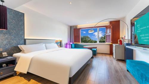 a bedroom with a large white bed and a window at Houhai Hotel in Beijing