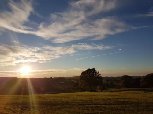 a sunset in a field with the sun in the sky at Hotel Cuba Libre in Vijlen