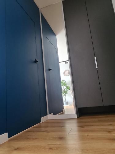 an empty room with blue walls and wooden floors at Posnania Comfort Apartment, free parking, self check-in 24h in Poznań