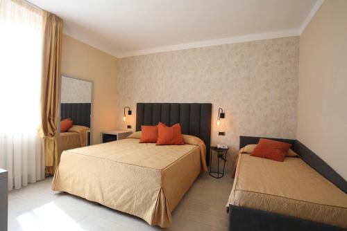 a hotel room with two beds with orange pillows at Hotel Tirrenia in Viareggio