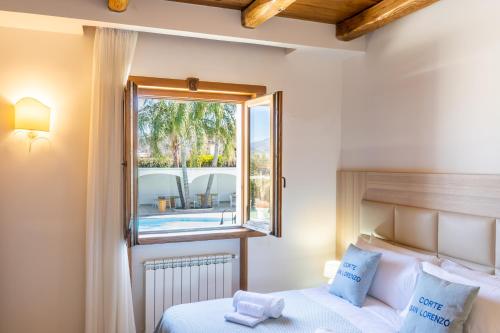 a bedroom with a bed and a window with a view of a pool at Corte San Lorenzo in Sant'Egidio del Monte Albino