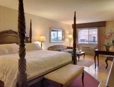 Merced Inn & Suites في ميرسيد: غرفة نوم مع سرير وغرفة معيشة