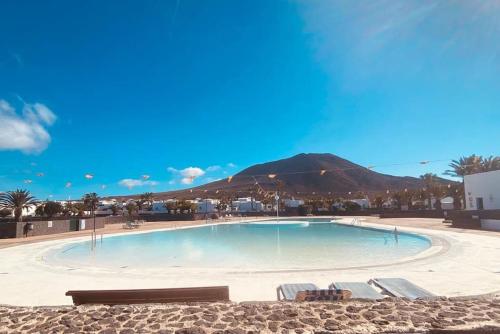 a swimming pool with chairs and a mountain in the background at Villa Maranvi in Playa Blanca