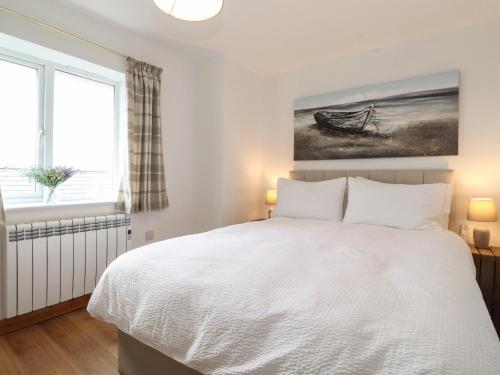 a bedroom with a white bed and a window at Coastal Nest 30 Union Street in Seahouses