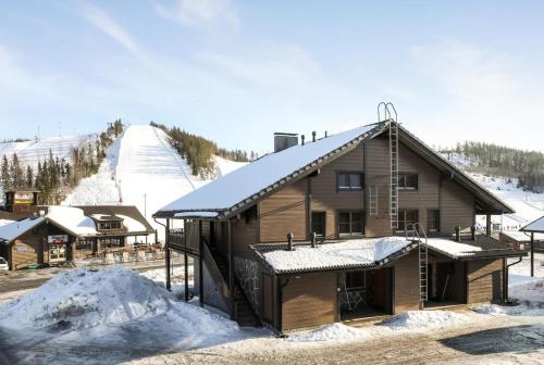 a log cabin with snow on the roof and a ski slope at Himos Mökki superior - Chalet Cottage superior ski-in-ski-out in Jämsä