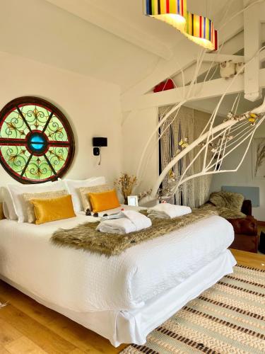 une chambre avec un grand lit blanc avec une fenêtre dans l'établissement Cabane Spa Sauna, à Ville-sur-Jarnioux