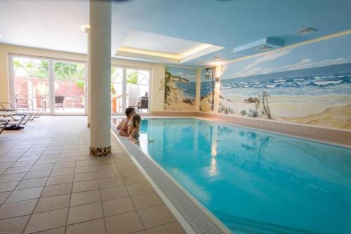 a child sitting in a swimming pool in a house at Hotel Sonnenklahr mit Pool in Göhren