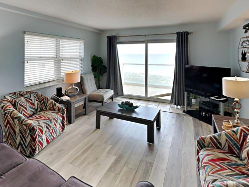 a living room with a couch and a tv and a table at Regency Towers #501 West in Pensacola Beach