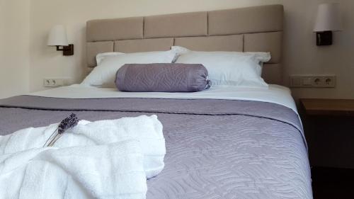 uma cama grande com lençóis brancos e uma almofada roxa em Marisa Apartments Hvar II em Hvar